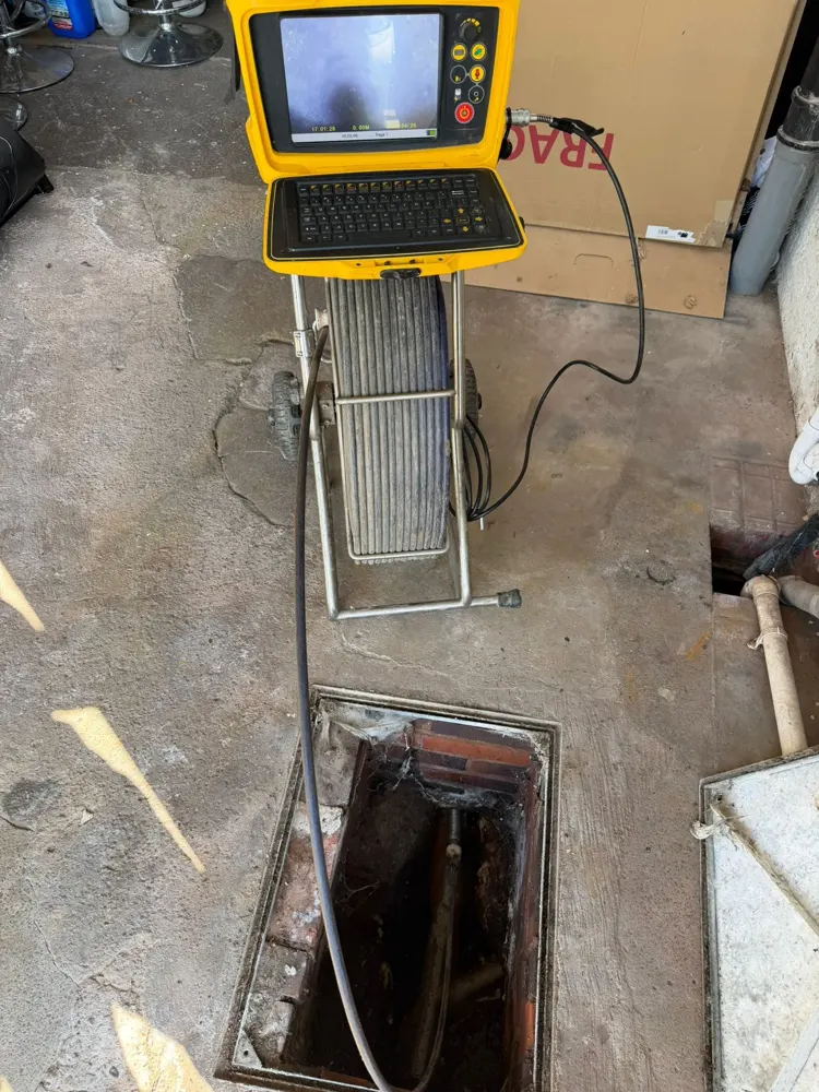 CCTV drain survey monitor beside an open drain