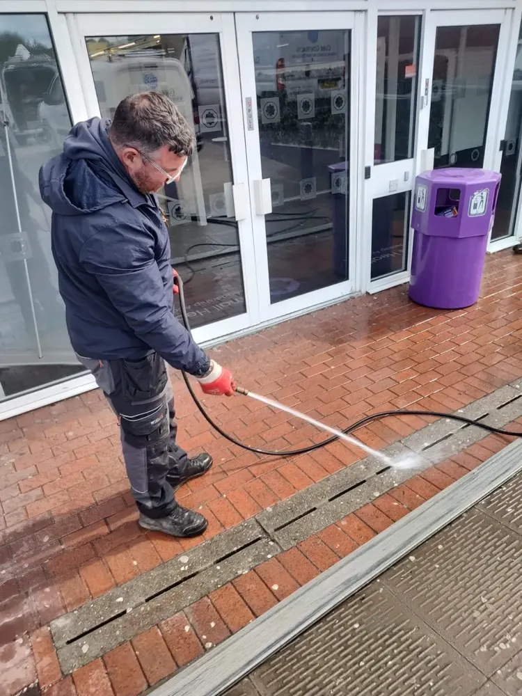 Engineer jet washing a commercial yard drain