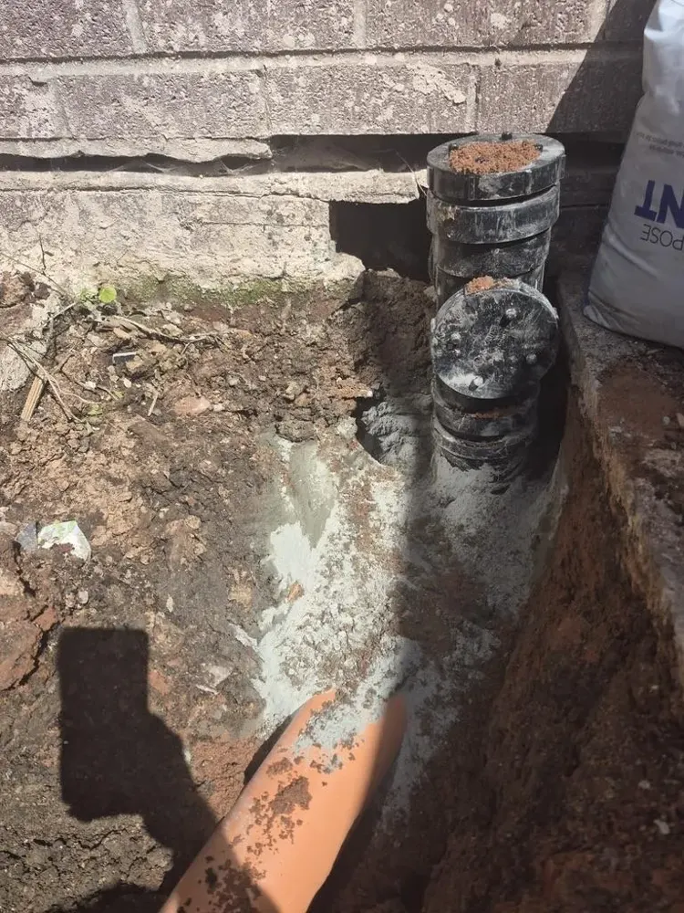 New orange drain pipe laid in an excavated trench